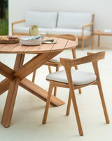 Silla de jardín Bok de Ethnicraft, junto a una mesa de comedor en una terraza