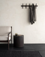 Perchero de pared PI de Ethnicraft con una prenda colgada junto a un sillón