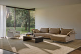 Composición modular Senso de Joquer con base suspendida, brazos en L y asiento continuo en el módulo principal, junto a una chaise en un salón.