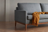 Detalle de ambiente del sofá K373 de Scandinavian Upholstery con base de madera y tapizado gris.