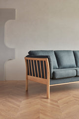 Sofá K129 de Scandinavian Upholstery con brazos de listones de roble lacado en un ambiente interior.
